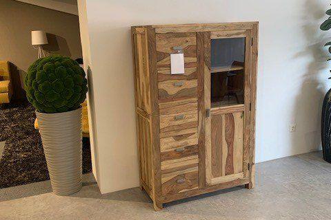 Rustikale Vitrine aus Massivholz mit Schubladen und Glastür in moderner Wohnzimmerausstellung mit Pflanzen.
