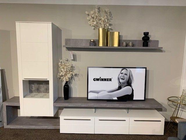 Kompakte TV-Wand in Weiß mit grauen Elementen, Wandregal und dekorativen Accessoires.