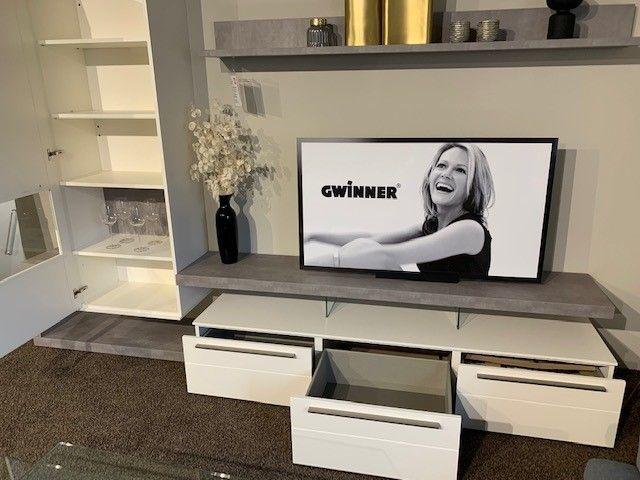 Weiße TV-Möbel mit grauen Akzenten, integriertem Fernseher und Schubladen in Möbelhaus-Ausstellung