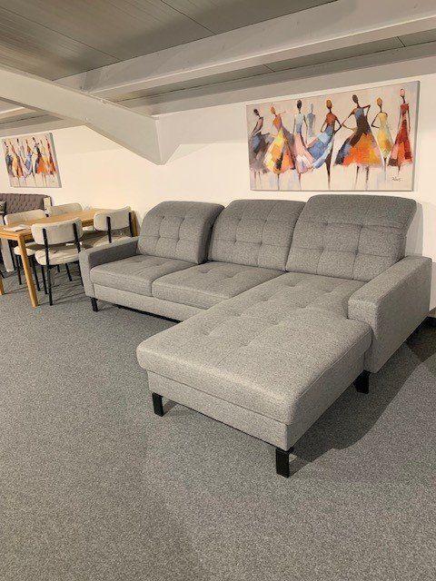 Graue Stoff-Eckcouch mit Chaiselongue und dunklen Holzfüßen unter Dachschräge in Möbelhaus-Keller.