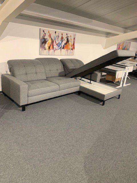 Multifunktionale Eckcouch mit geöffnetem Bettkasten unter der Chaiselongue zeigt praktischen Stauraum.
