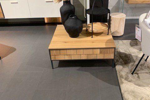 Moderner Couchtisch aus Holz mit schwarzer Schublade, dekoriert mit schwarzen Vasen in Möbelhaus-Ausstellung.
