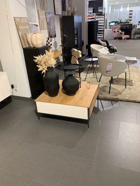 Holz-Couchtisch mit weißer Schublade in Möbelhaus-Showroom, umgeben von verschiedenen Wohnmöbeln