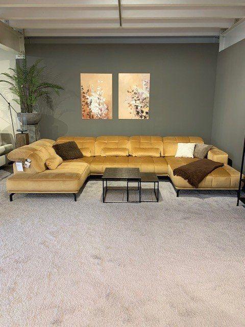 Große U-förmige Ledercouch in Senfgelb mit schwarzen Metallcouchtischen vor grauer Wand.