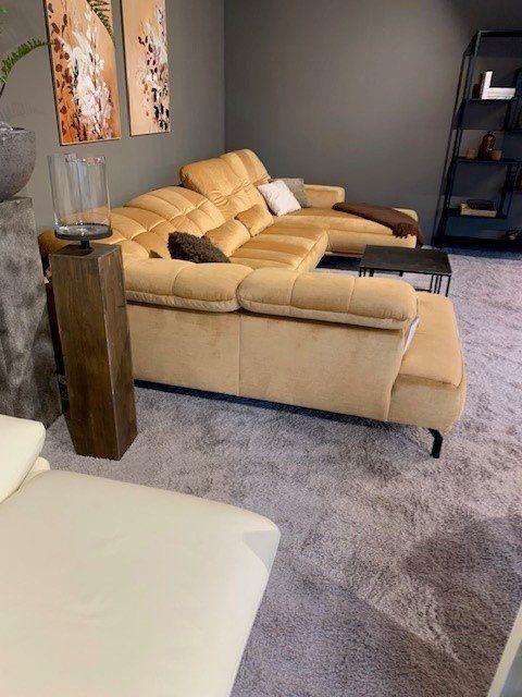Gelbes Ledersofa mit verstellbaren Kopfstützen und Holz-Beistelltisch in Showroom-Ambiente.