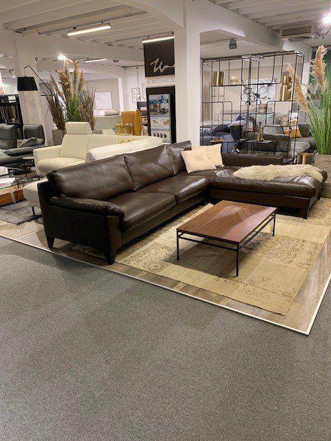 Leder-Ecksofa in Schwarz mit modernem Couchtisch in weitläufiger Möbelhaus-Ausstellung.