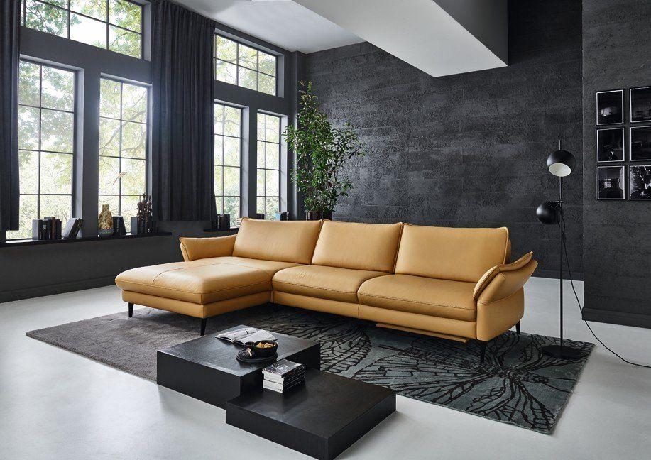 Cognacfarbene Leder-Eckcouch mit Chaiselongue und schwarzem Couchtisch in Industrial-Loft mit Betonwand.