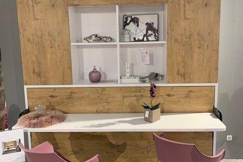 Moderner Arbeitsplatz mit weißer Tischplatte, Eichenholz-Wandregal und zwei rosa Designerstühlen.