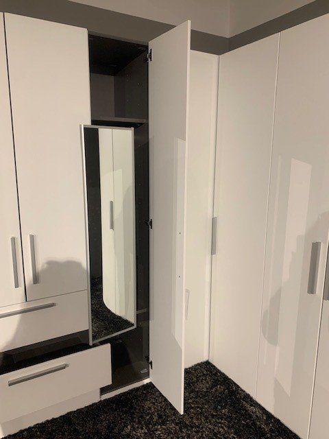 Detailansicht der Eckschrank-Innenausstattung mit integriertem Spiegel und optimaler Raumnutzung.