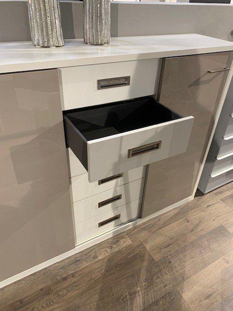Detailansicht einer geöffneten Sideboard-Schublade mit schwarzem Innenbereich und modernen grauen Metallgriffen.