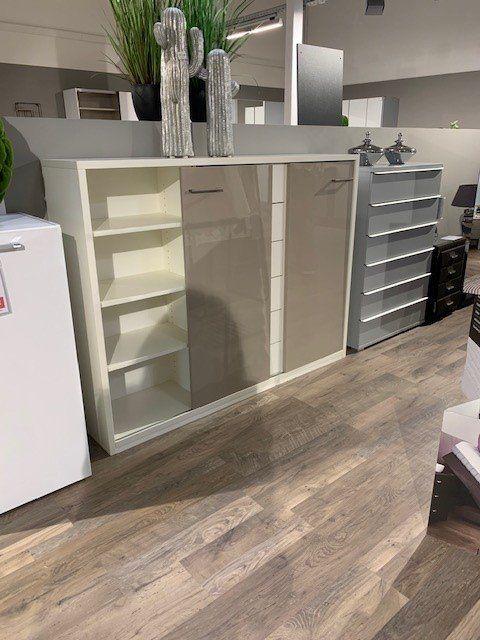 Geöffnetes weißes Sideboard zeigt Innenaufteilung mit Regalbrettern und offenen Fächern neben Schubladen-Elementen.