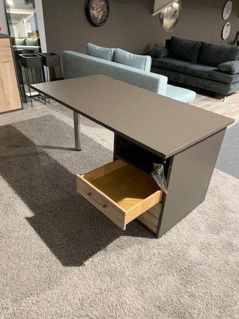 Anthrazitfarbener Schreibtisch mit geöffneter Holzschublade in modernem Wohnzimmer mit grauer Couch.