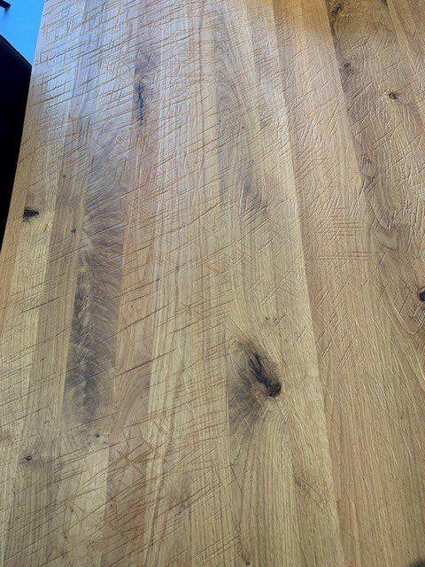 Detailaufnahme der Holztischplatte mit ausdrucksvoller Maserung, Astlöchern und natürlicher Oberflächenstruktur des Massivholzes.