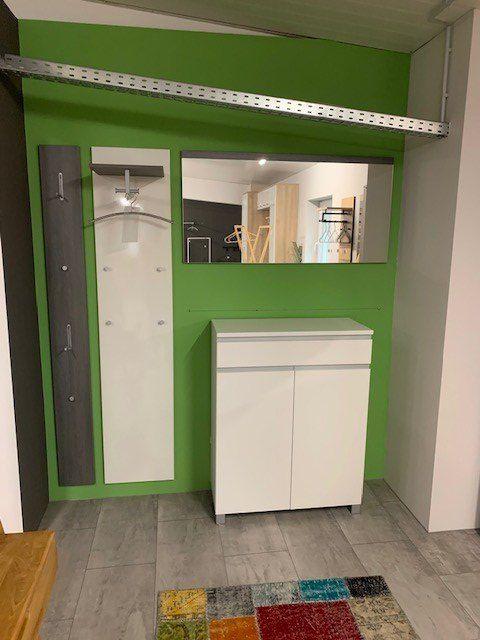 Modernes Garderoben-Set in grüner Wandnische mit weißem Schrank, Spiegel und grauer Garderobenpanele mit Haken.