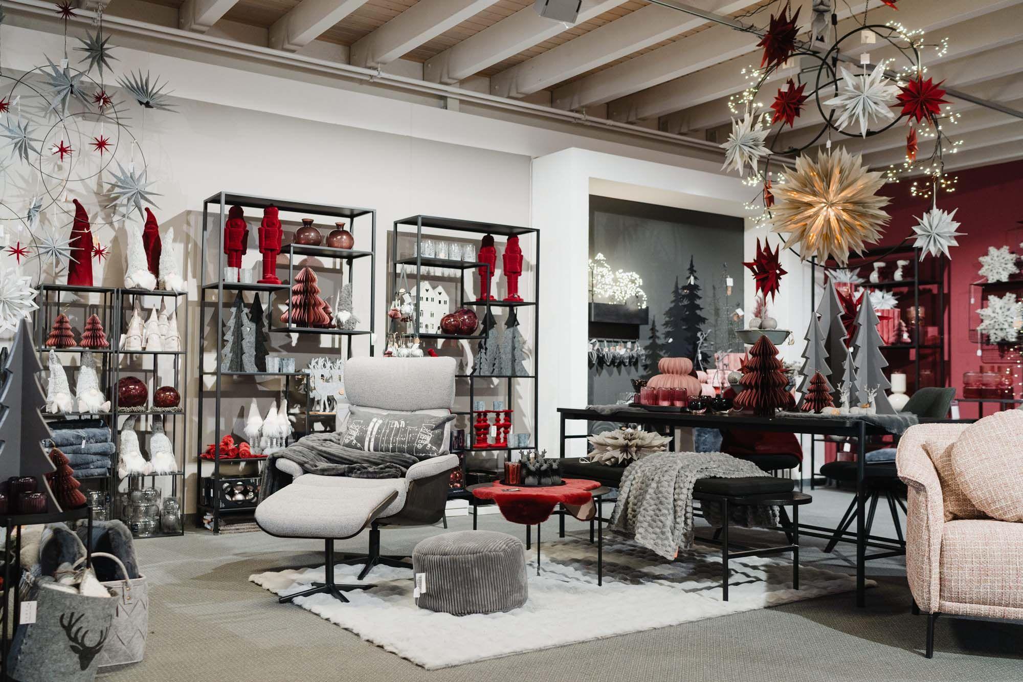 Weihnachtlich dekorierter Wohnbereich mit gemütlichem Sessel, roten und grauen Dekofiguren sowie leuchtenden Sternen.