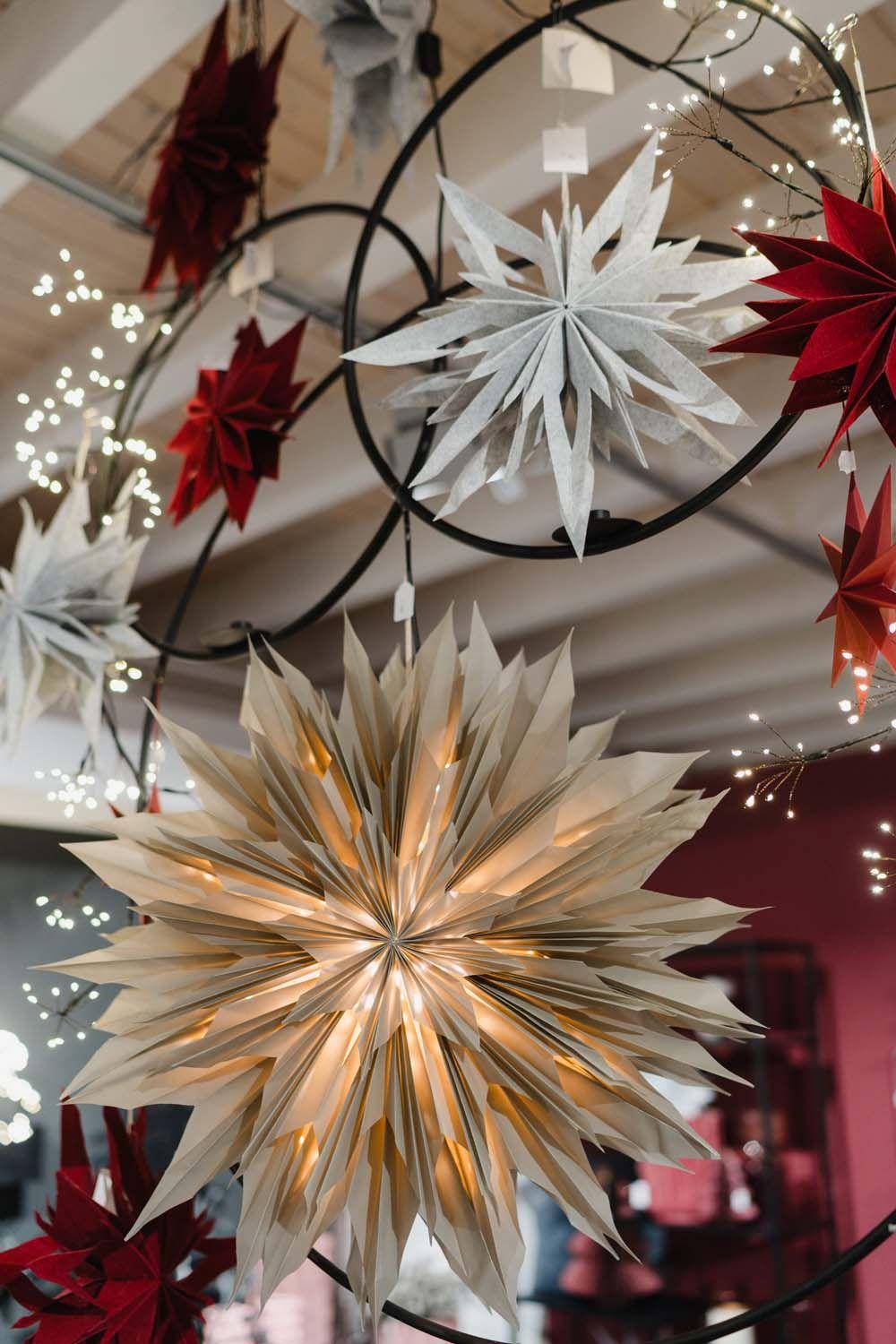Große beleuchtete Papiersterne in Weiß und Rot hängen dekorativ von der Decke.