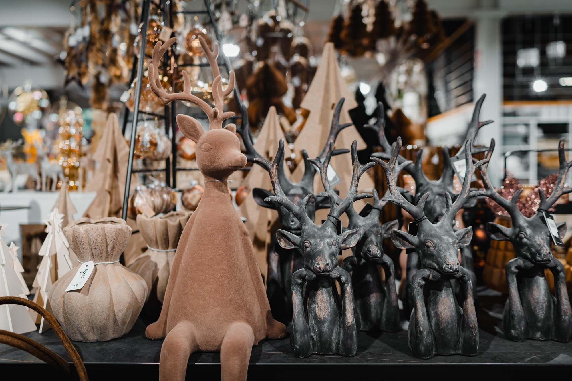Deko-Arrangement mit einem sitzenden braunen Rentier und mehreren dunklen Rentierfiguren.