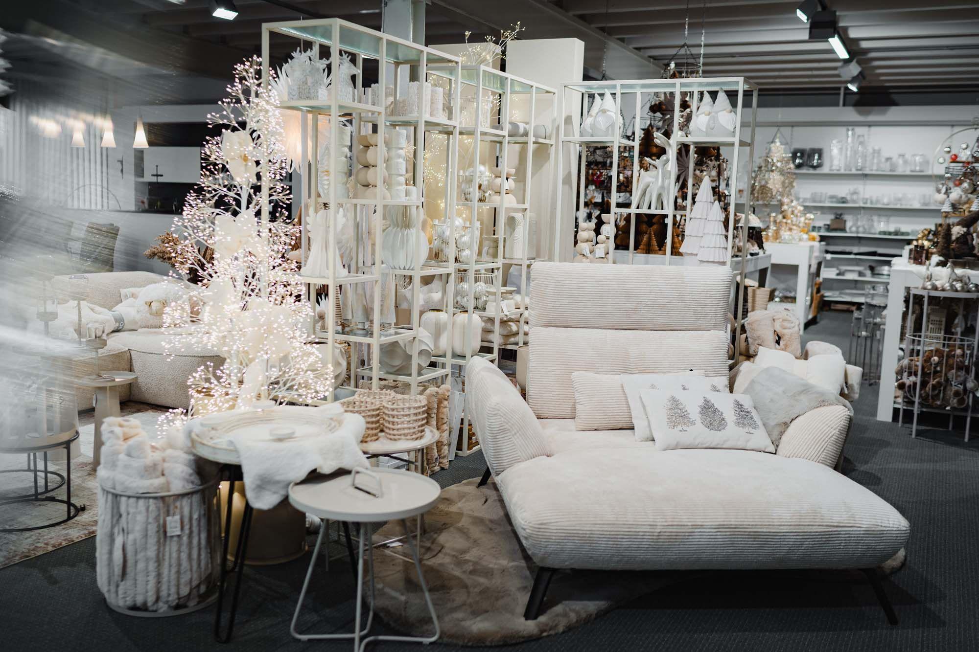 Skandinavisch inspirierte Winterlandschaft in Weiß mit Sofa, Dekofiguren und leuchtenden Bäumen.