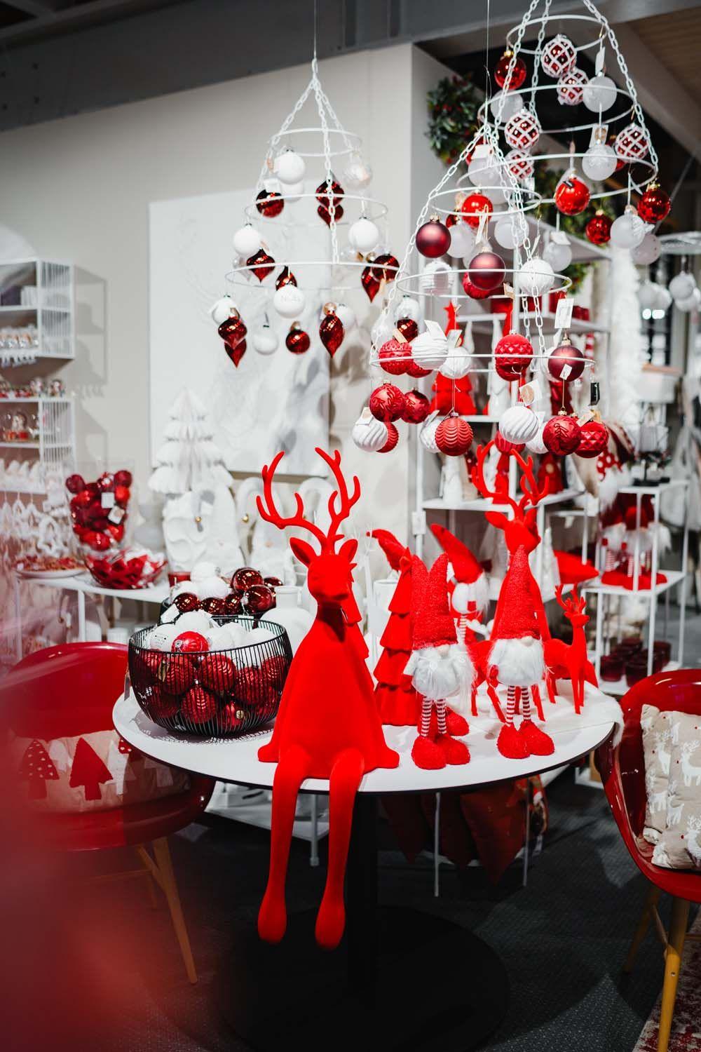 Weihnachtstisch mit roten Rentierfiguren, Weihnachtskugeln und hängenden Dekoarrangements in Rot und Weiß.