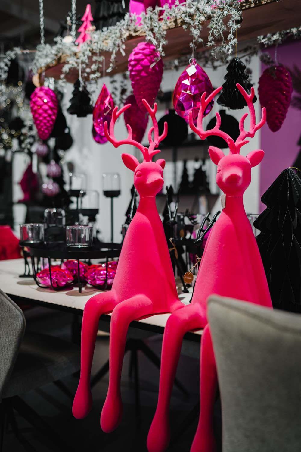 Zwei pinke Rentierfiguren zwischen glänzender pinker Weihnachtsdekoration.
