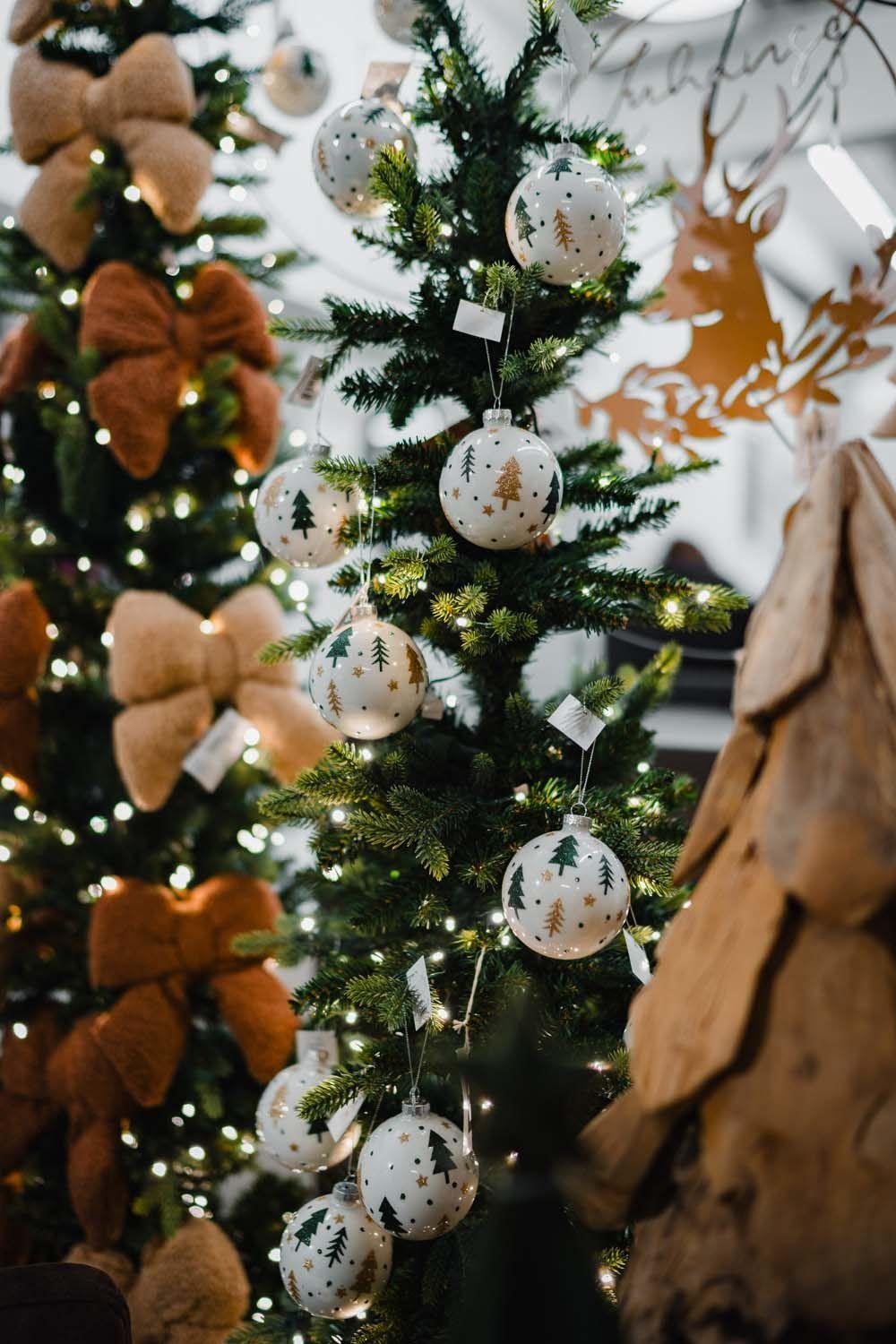 Geschmückter Weihnachtsbaum mit weißen Kugeln im Tannenbaum-Design und warmen Lichtern.