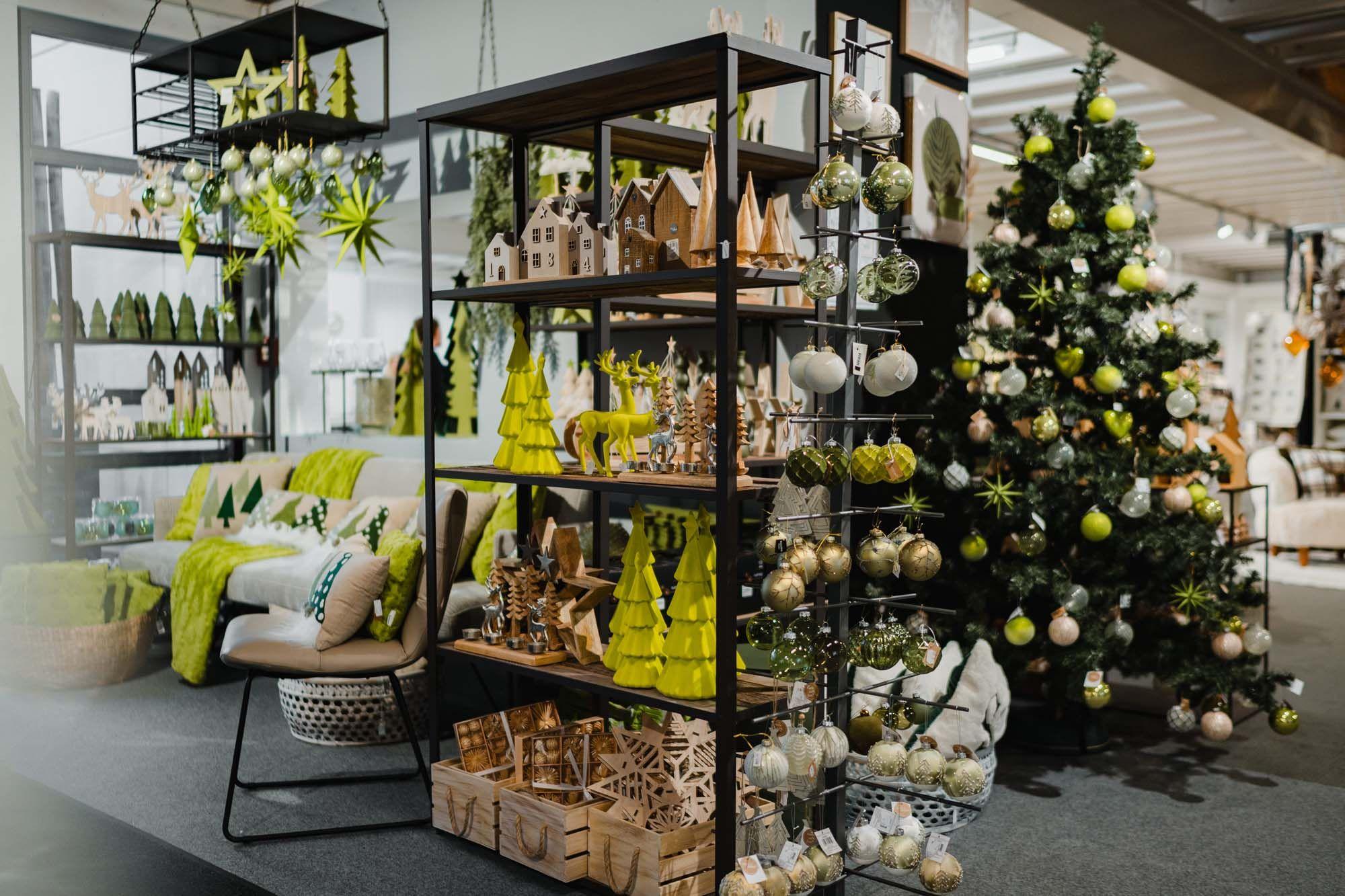 Ausstellung mit grüner Weihnachtsdeko, Holzfiguren und festlich geschmücktem Christbaum.
