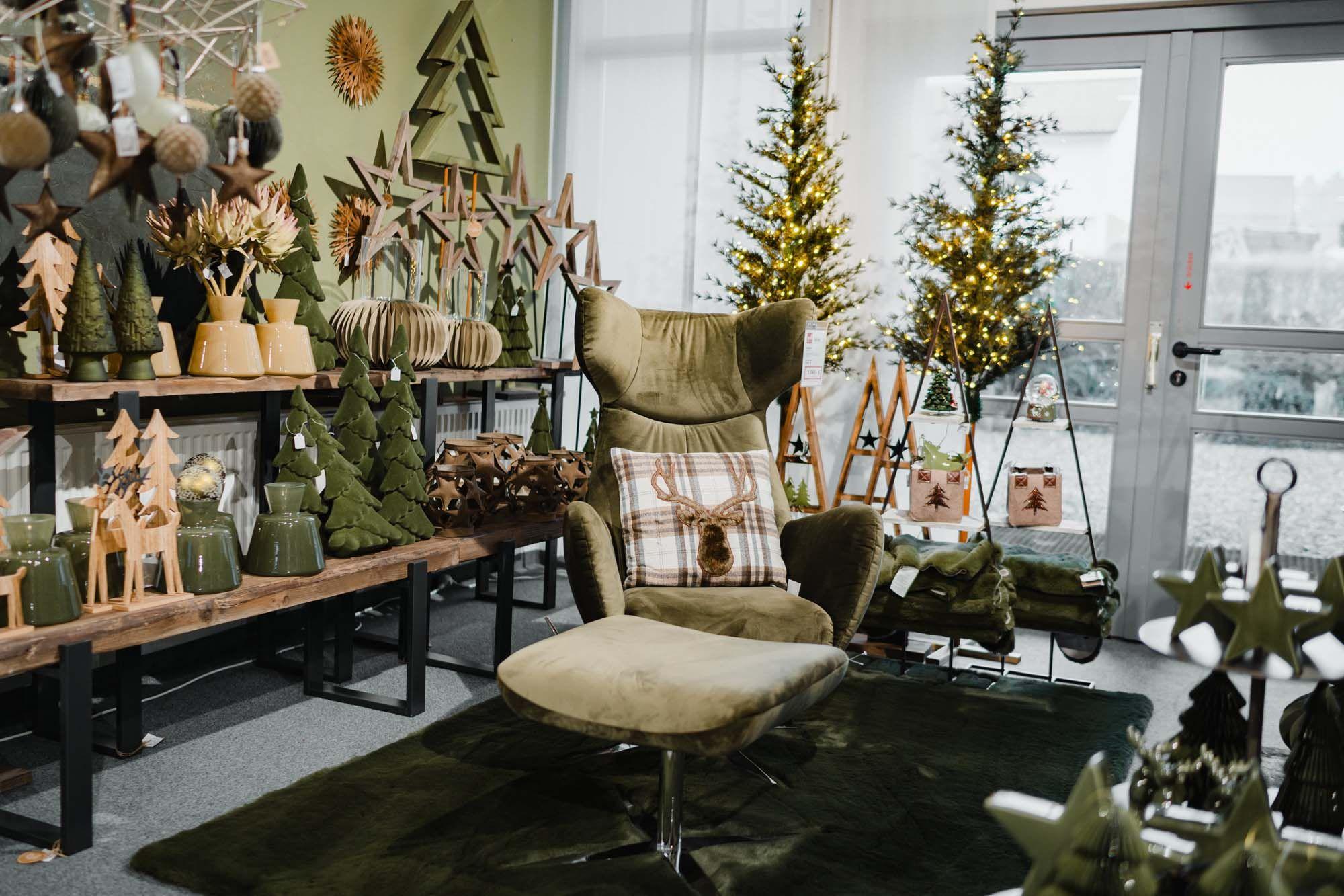 Gemütlicher grüner Wohnbereich mit weihnachtlicher Deko, beleuchteten Bäumen und Sessel mit Hirschkissen. Gemütlicher grüner Wohnbereich mit weihnachtlicher Deko, beleuchteten Bäumen und Sessel mit Hirschkissen.