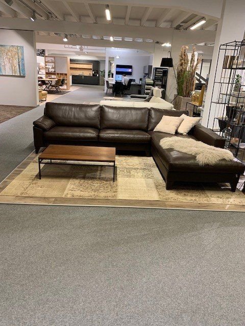 Schwarze Leder-Eckcouch mit Chaiselongue und Holz-Couchtisch in großem Möbelhaus-Showroom.