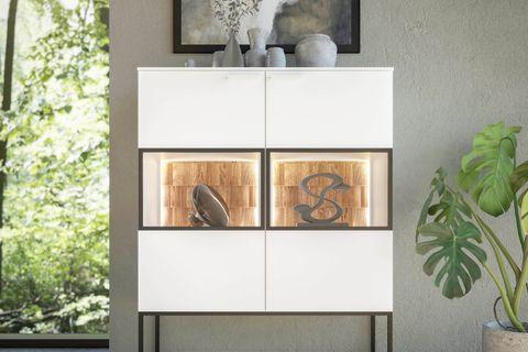 Weißes Highboard mit LED-beleuchteten Glasfächern und Holzrückwand, dekoriert mit Vasen vor großem Fenster